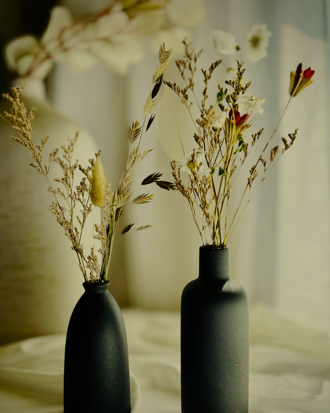 dried flower stems and branches in two black vases
