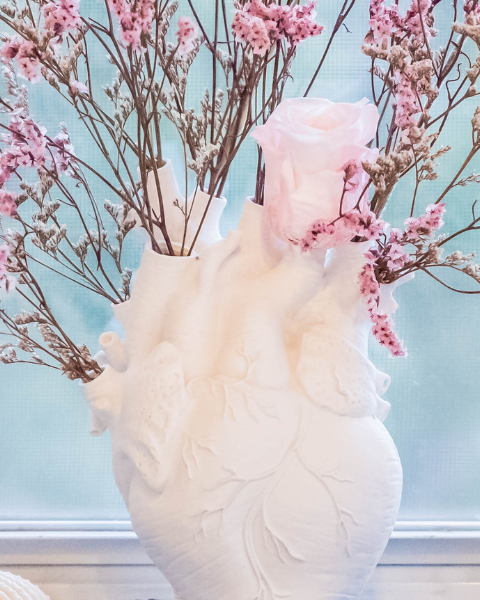 Pink colored dried flowers in a heart shaped vase