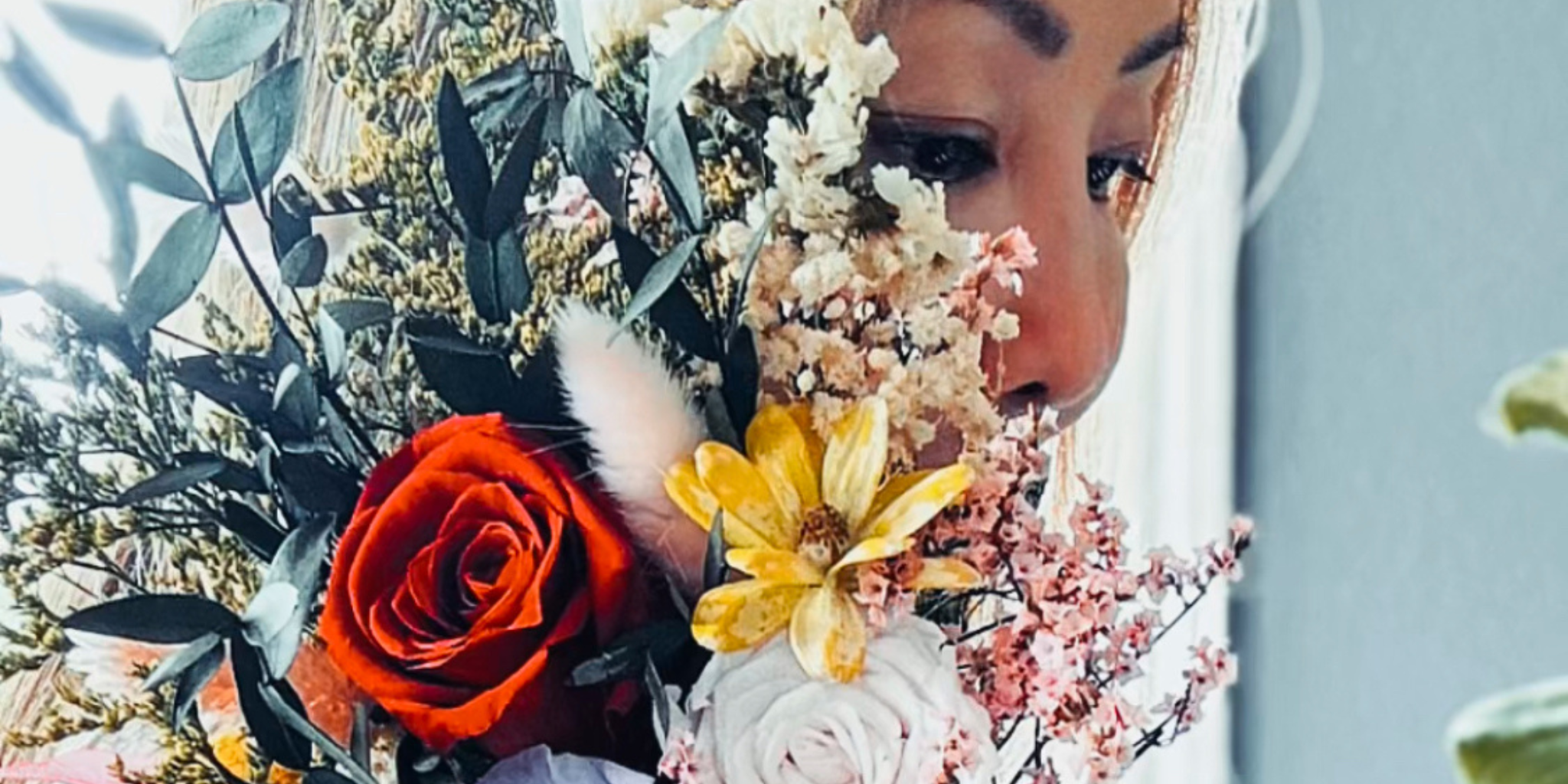 a woman holding a dried flower bouquet next to her face